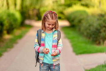 Little girl using sanitizer after school