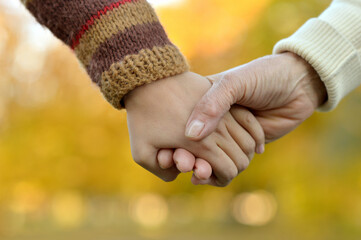 Boy and grandmother hands together over natural background