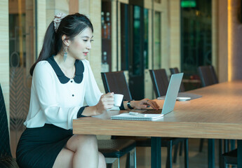 Fototapeta na wymiar Asian businesswoman on a coffee break. Using laptop computer.