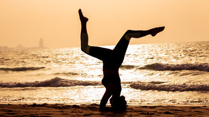 young woman doing yoga on the beach