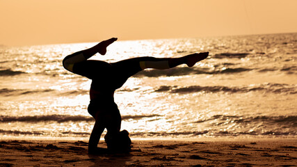 young woman doing yoga on the beach