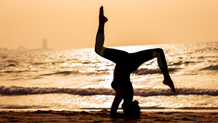young woman doing yoga on the beach