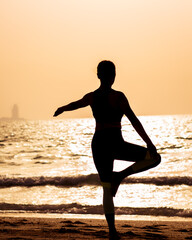 young woman doing yoga on the beach