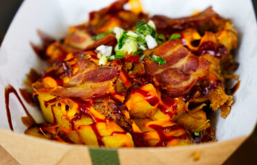 French fries with bacon hot sauce served on a paper dish
