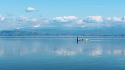 A fisherman in a scenic landscape of blue
