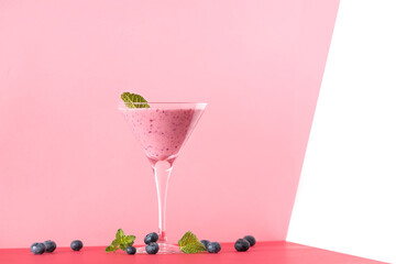 Blueberry smoothie cup with several blueberries on a red background.