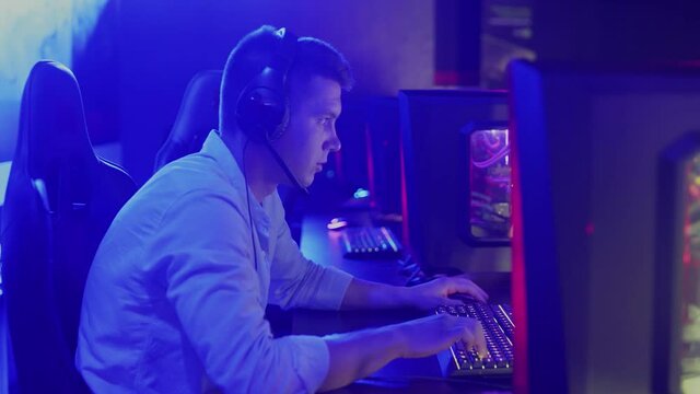 Side view portrait shot of young man with headset winning a shooter game round in cybersport competition