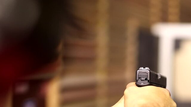 shooter shoots a pistol, close-up, focus on the pistol, soft focus
