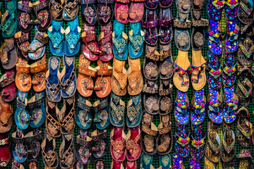 Fototapeta premium Kolhapuri Chappal - kolorowe i różnorodne damskie etniczne obuwie wystawiane w sprzedaży na targu ulicznym w Indiach. Kolhapuri Chappal w Indiach są zwykle noszone z etnicznymi strojami kultury indyjskiej.