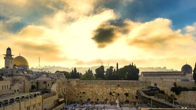 Beautiful time lapse of sunrise clouds moving fast over the Temple Mount: Dome of the Rock, Western Wall and Al Aqsa Mosque; with Jewish people praying in sections because of covid-19 regulations 