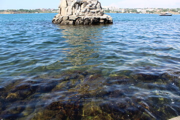 Photo of sea water of the black sea. Rocks visible through the water. Reflections on the water