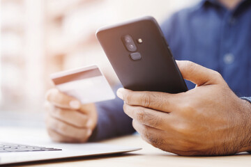 male hands holding credit card and using phone and computer laptop. Online shopping purchase Sell or Payment.