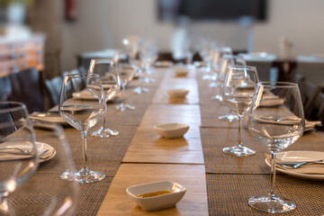 Mesa de restaurante para multiples comensales con copas y cubiertos y aceite de oliva
