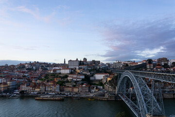 Fototapeta na wymiar Porto view, with Dom Luís Bridge and Douro river. Sunset, blue sky and clouds. Boats on the river