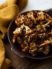 Rustic spiced, roasted cauliflower with roasted vegetables in natural light.