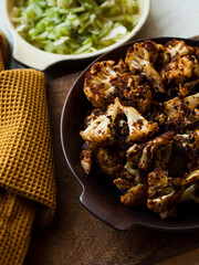 Rustic spiced, roasted cauliflower with roasted vegetables in natural light.