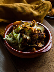 Rustic spiced, roasted cauliflower with roasted vegetables in natural light.