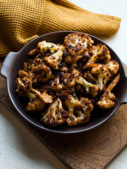Rustic spiced, roasted cauliflower with roasted vegetables in natural light.
