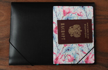 Diary, passport and black folder on the background of a wooden table