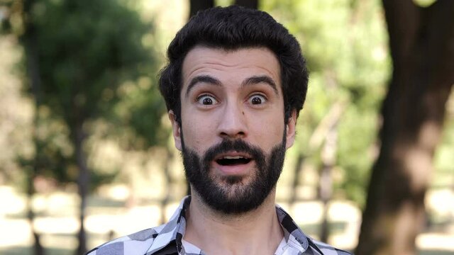 young man at park  pretends an expression of wonder in front of the camera