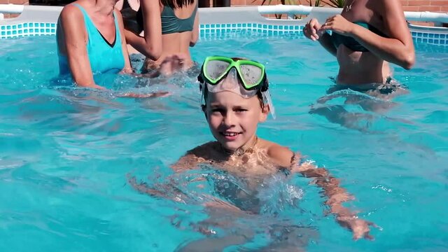 Child swimming in a swimming pool while people practicing water aerobics