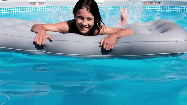 Child having fun swimming and relaxing in the blue water of a swimming pool while cooling off on a summer day