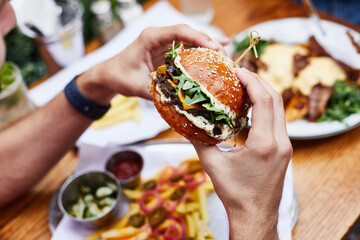 Close up of tasty burger. Male hands holding hamburger at street food festival. Eating Fast Food.