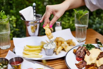 Eating Fast Food. Close up of woman hand holding delicious shrimps crispy in outdoor cafe on sunny summer day.