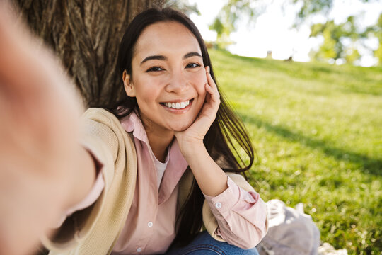 Image of cheerful asian student woman taking selfie photo and smiling