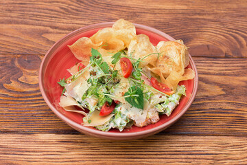salad with chips, cheese and herbs in a plate on a wooden table