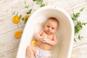 a small child bathes in a bath with foam and oranges, children are allergic to citrus