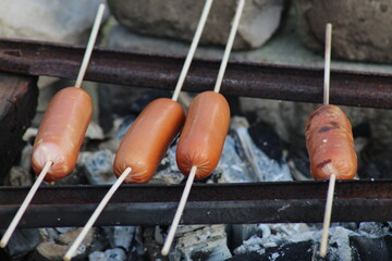 Fried sausages on the fire in nature. The food at the picnic