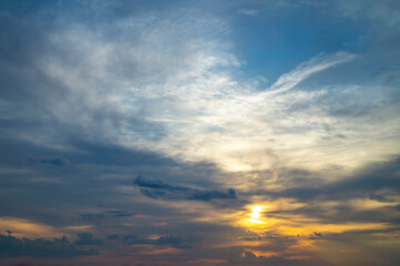 Naklejka na ściany i meble Sun peeking through the clouds at sunset
