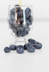 
Blueberries on a white background. And also in a glass with a yellow tube. On a gray background.