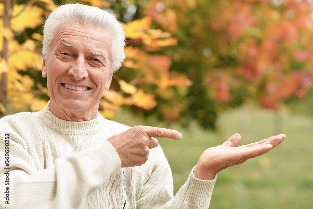 Poster Portrait of a senior man on a walk , pointing at something