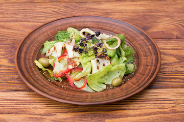 salad with cheese peppers, lettuce and arugula in a plate on a wooden background