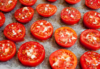 Chopped tomatoes with spices, garlic and olive oil on parchment paper. Close-up. Sun-dried tomatoes