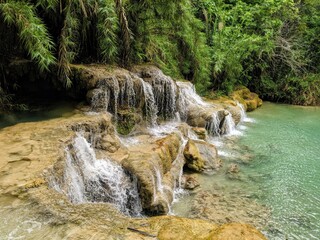 Wasserfall Kaskaden vor Bäumen und türkisfarbenem Wasser