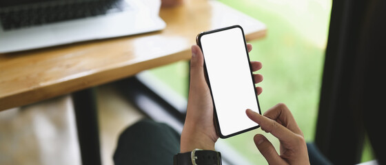 Cropped image of the hand is using a mockup mobile phone.