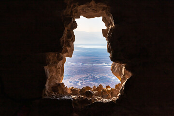 Dawn  through a breach in the wall at the Massada Ruins, a fortress built by Herod the Great on a cliff-top off the coast of the Dead Sea. Destroyed by the Romans in the 1st century AD e.