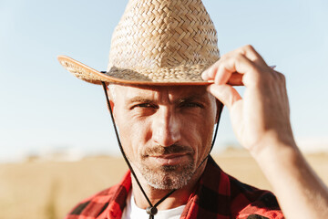 Image of adult man looking at camera while standing at cereal field