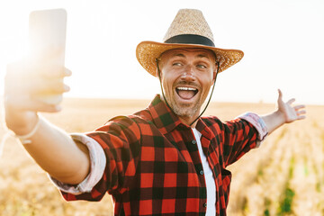 Image of excited adult man taking selfie on cellphone at cereal field
