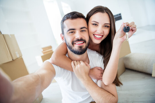 Self-portrait of his he her she nice attractive cheerful tender married spouses embracing holding in hand key rent loan lease purchase accommodation place at flat light white interior house