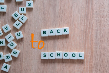 children make up from letters on a wooden table the words back to school, the concept of the beginning of the school year, homework, lessons