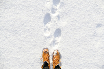 Top view of yellow shoes / boots footprint in fresh snow. Winter season. 