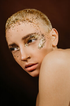 Beautiful woman with creative make up and golden glitter over the face. Short hair woman with perfect skin and make up