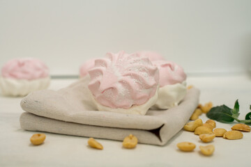 composition of delicate airy marshmallows and peanuts and mint leaves. low calorie sweets