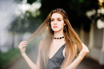 Naklejka premium portrait of beautiful young girl in black dress outdoors, attractive woman with long hair