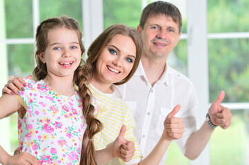 Happy parents and daughter posing in room