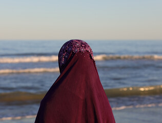 young arab with veil on her head by the sea in summer